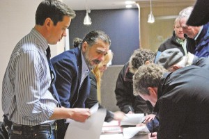 Councillors-elect Jeff Thom, Tom Mrakas, and Councillor Sandra Humfyes assist residents in registering before this week's meeting.